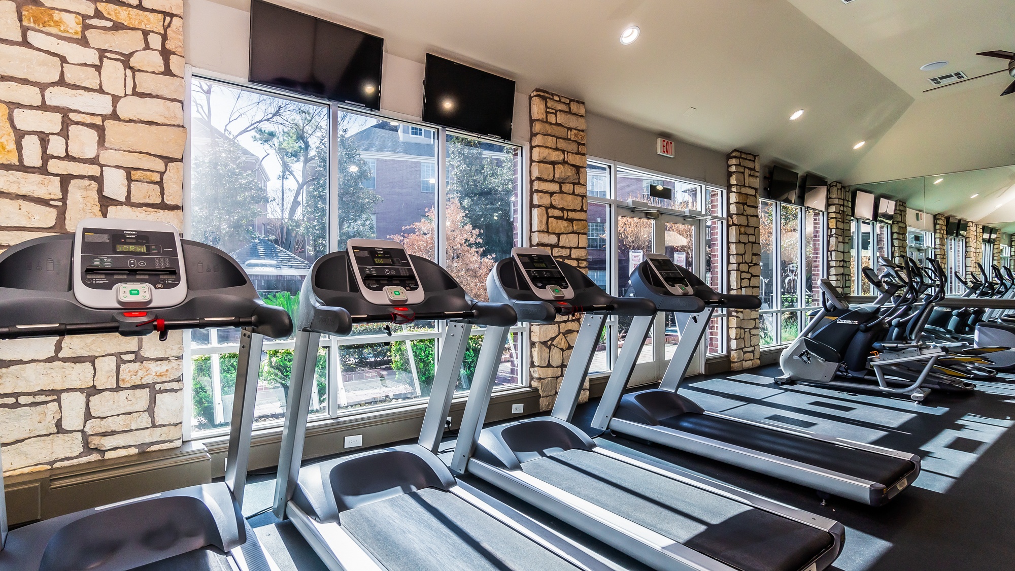 A gym with treadmills and a brick wall.